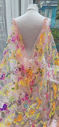 a white mannequin wearing a pink and yellow shawl with flowers on it