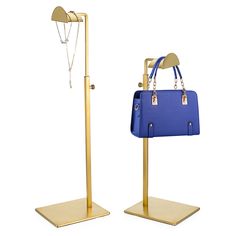 two gold and blue handbags on stands with chains hanging from the handles, one holding a purse