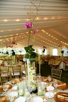 a vase with flowers on top of a table filled with plates and wineglasses