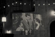 a building with lights hanging from it's sides and an image of a man in a suit on the wall