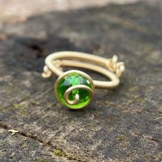 This ring was inspired from the classic video game for Nintendo 64,  The Legend of Zelda, Ocarina of Time.  This ring contains the Kokiri's Emerald.  This ring has green crystal, and silver plated gold colored wire.  The ring is completely adjustable with an immense amount of detail that can only be appreciated in person.  This ring is very comfortable and one of a kind so get your Zelda stone today!  All rights reserved by GuiltyGeeks© Adjustable Green Crystal Gemstone Ring, Green Crystal Round Ring As Gift, Green Crystal Round Ring Gift, Green Crystal Round Ring For Gift, Adjustable Green Crystal Open Ring, Adjustable Green Crystal Ring For Promise, Adjustable Green Crystal Promise Ring, Adjustable Green Emerald Ring, Handmade Adjustable Green Emerald Ring