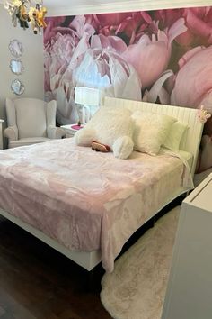 a large bed sitting in a bedroom next to a wall with pink flowers on it