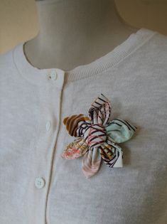 a woman wearing a white sweater with a colorful flower on it's lapel