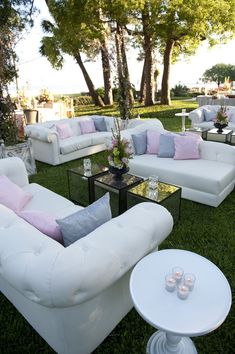 a bunch of couches and chairs sitting in the grass with candles on top of them