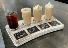 three drinks on a wooden tray with chalk writing