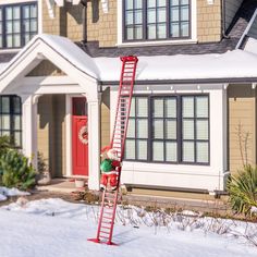 a red fire hydrant sitting next to a ladder in front of a house with snow on the ground