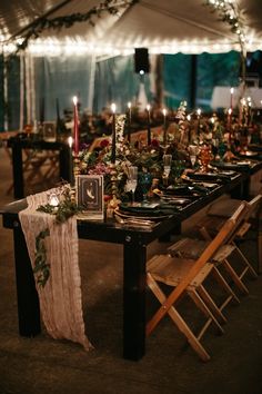 a table set up with candles, flowers and greenery for an outdoor wedding reception