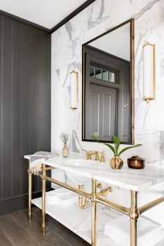 a bathroom with marble counter tops and gold fixtures, along with a large mirror above the sink