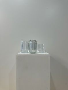 two glass vases sitting on top of a white block