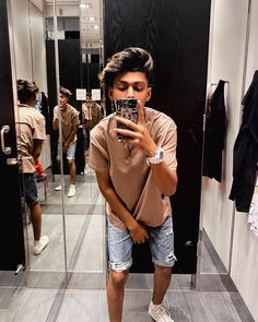 a man taking a selfie in front of a mirror while wearing shorts and a t - shirt