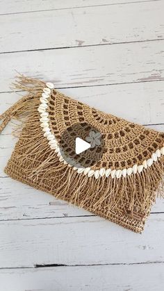 an image of a purse with fringes on the front and side, sitting on a white wooden surface