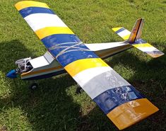 a small airplane sitting on top of a lush green field next to a grass covered field