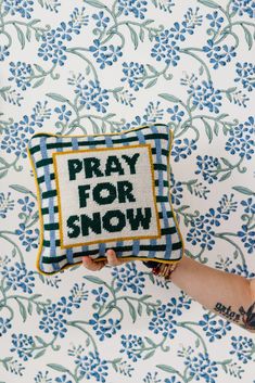 a person holding a pillow that says pray for snow