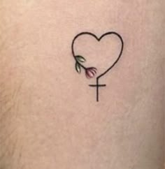 a cross and heart tattoo on the back of a woman's thigh, with an arrow in the shape of a heart