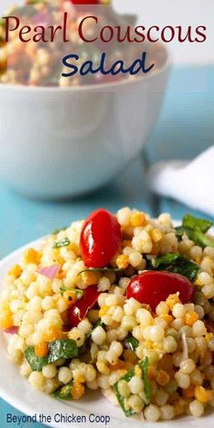 a white plate topped with corn salad next to a bowl filled with tomatoes and basil