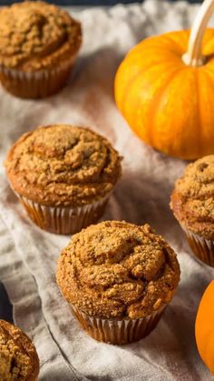 several muffins sitting on top of a piece of paper next to pumpkins