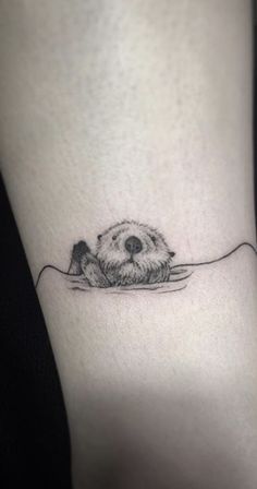 a small black and white animal tattoo on the ankle