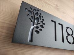 a metal house number sign with a tree on it