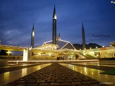 a large building lit up at night with lights on it's sides and two towers in the background