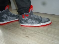 a person standing on top of a wooden floor wearing gray and red sneakers with white outs