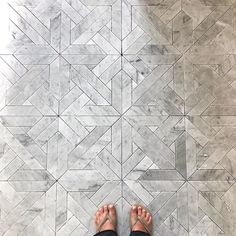 a person standing on a tile floor with their feet propped up in the middle of it