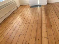 an empty room with hard wood floors and white walls