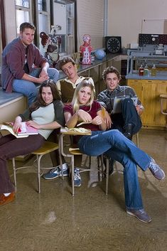 a group of young people sitting around each other in a room with lots of windows