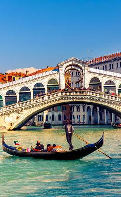 a gondola in the middle of a canal with buildings on both sides and a bridge crossing over it