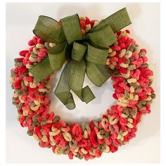 a red and green wreath with a bow on it's side, sitting on a white surface