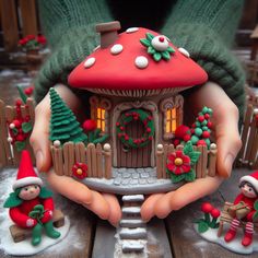 a close up of a person holding a small toy house with christmas decorations on it