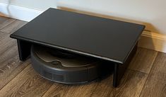 a black coffee table sitting on top of a hard wood floor next to a wall