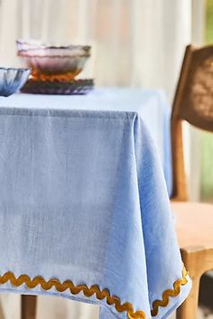 a blue table cloth with gold scalloped edges sits on a wooden chair in front of a window