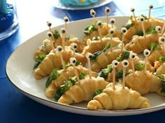 a white plate topped with croissants covered in broccoli and googly eyes