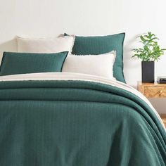 a bed with green sheets and white pillows