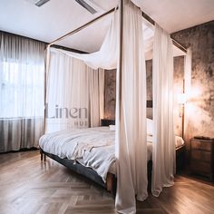 a canopy bed with white drapes in a bedroom