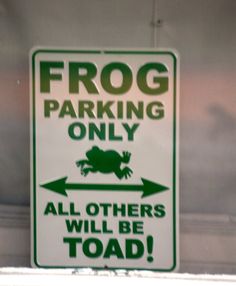 a frog parking only sign hanging from the side of a building with an arrow pointing to it