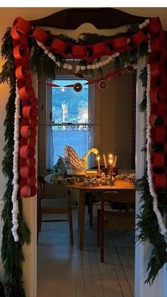 an archway decorated with red and white ribbon, candles and garlands for the holiday table