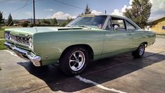 an old green car parked in a parking lot