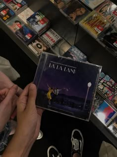 a person holding up a cd in front of a book shelf