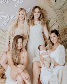 three women and a baby are posing for a family photo in front of a sign