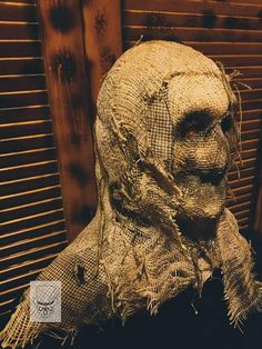 a creepy looking scarecrow head sitting in front of a wooden wall with shutters