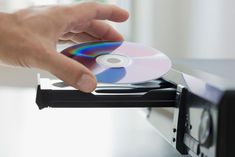 a hand is holding a cd in front of a computer screen with the disc on it