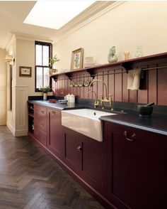 a kitchen with red cabinets and white sink under a skylight in the middle of it