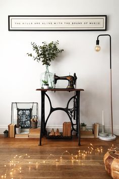 an old sewing machine sitting on top of a wooden table next to a vase with flowers