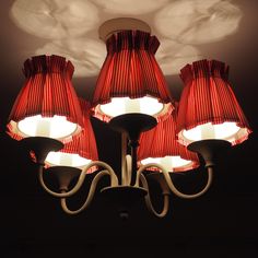 a chandelier with red shades hanging from it's ceiling