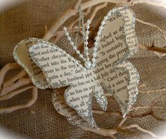 a book page butterfly with pearls on it's wings sitting on top of some branches