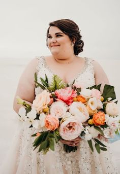 a woman in a wedding dress holding a bouquet of flowers and smiling at the camera