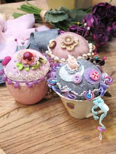 two cup cakes sitting on top of a wooden table next to flowers and other decorations