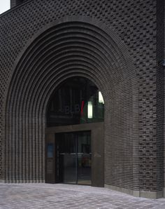 an entrance to a building with a clock on the wall and brick walkway in front