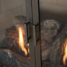 a close up of a metal door with fire in the background